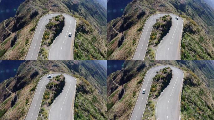 4k顶视图无人机航拍镜头，一辆白色经济型汽车在葡萄牙马德拉岛被悬崖包围的柏油路旁行驶。安全运输概念U