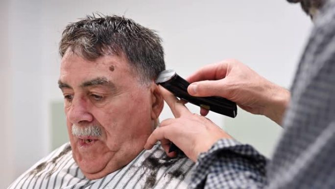 理发师在理发店修剪老人的头发。
