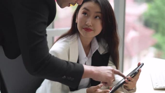 年轻的亚洲女商人使用平板电脑与团队分享想法
