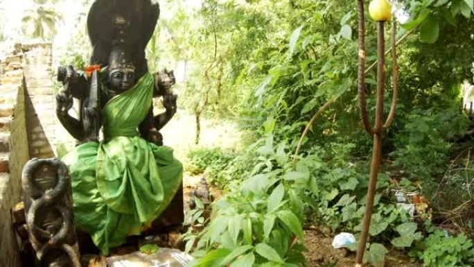 装饰着绿色衣服的印度女神黑色雕像蛇在树叶金属三叉戟中的图像