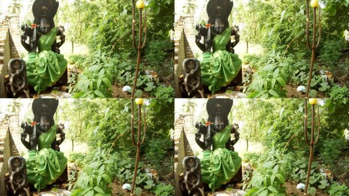 装饰着绿色衣服的印度女神黑色雕像蛇在树叶金属三叉戟中的图像