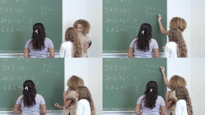一群小学年龄的女孩一起在黑板上写下数学问题的答案
