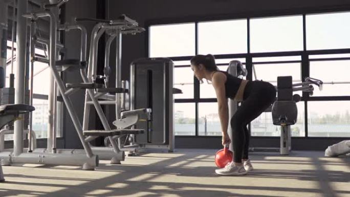 女人在健身馆用壶铃深蹲腿锻炼健康的生活方式肌肉建设者，运动运动女人训练耐力强锻炼。高清慢动作镜头电影