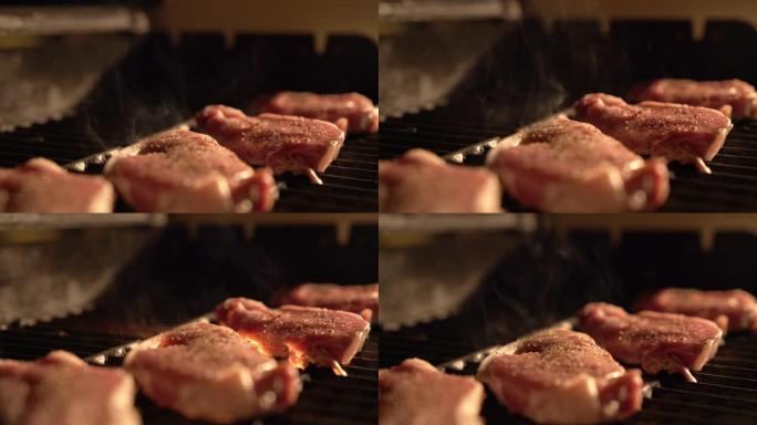 晚上在室外的热烤架上烤和烹饪调味的、未煮熟的、去骨的里脊肉猪排，由天井灯照亮