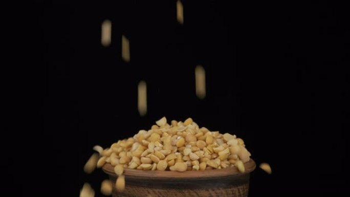 干豌豆的全谷粒落在躺在陶罐中的一束谷物上，从锅中掉了出来。特写。