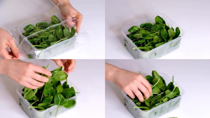 女人在白色桌子上用食物薄膜做食物菠菜。包装产品用透明聚乙烯食品薄膜卷。慢动作视频。