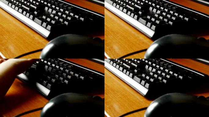 在木桌上的黑色键盘的特写镜头，一个小孩的手敲击按键，孩子们在游戏的帮助下早期掌握和学习计算机。