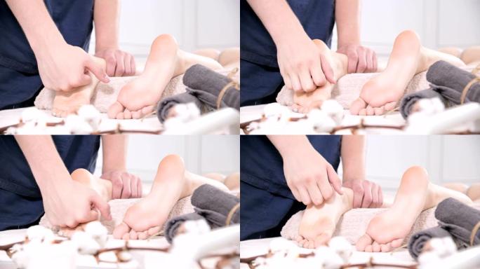 一位男性理疗师在美容和健康水疗中心对一名年轻女子进行足底和脚底按摩的特写镜头。足部和身体护理概念