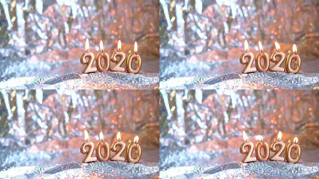 文本2020金色蜡烛燃烧。模糊的银色背景。复制空间。圣诞快乐，新年快乐。选择性聚焦。创意现场贺卡。4