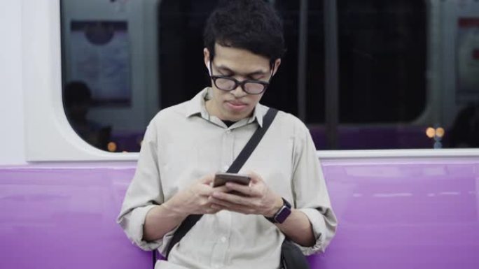 曼谷BTS午夜街市使用智能手机的亚洲男子