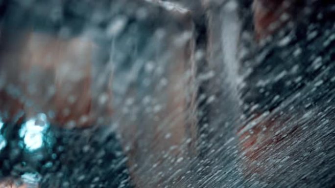 前车窗上的水特写。在玻璃上下雨。自动洗车。肥皂水沿着汽车玻璃流下。