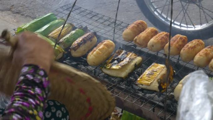 越南街头美食，烤米饭卷，里面装满香蕉。特写女人身体部分在街上准备早餐。