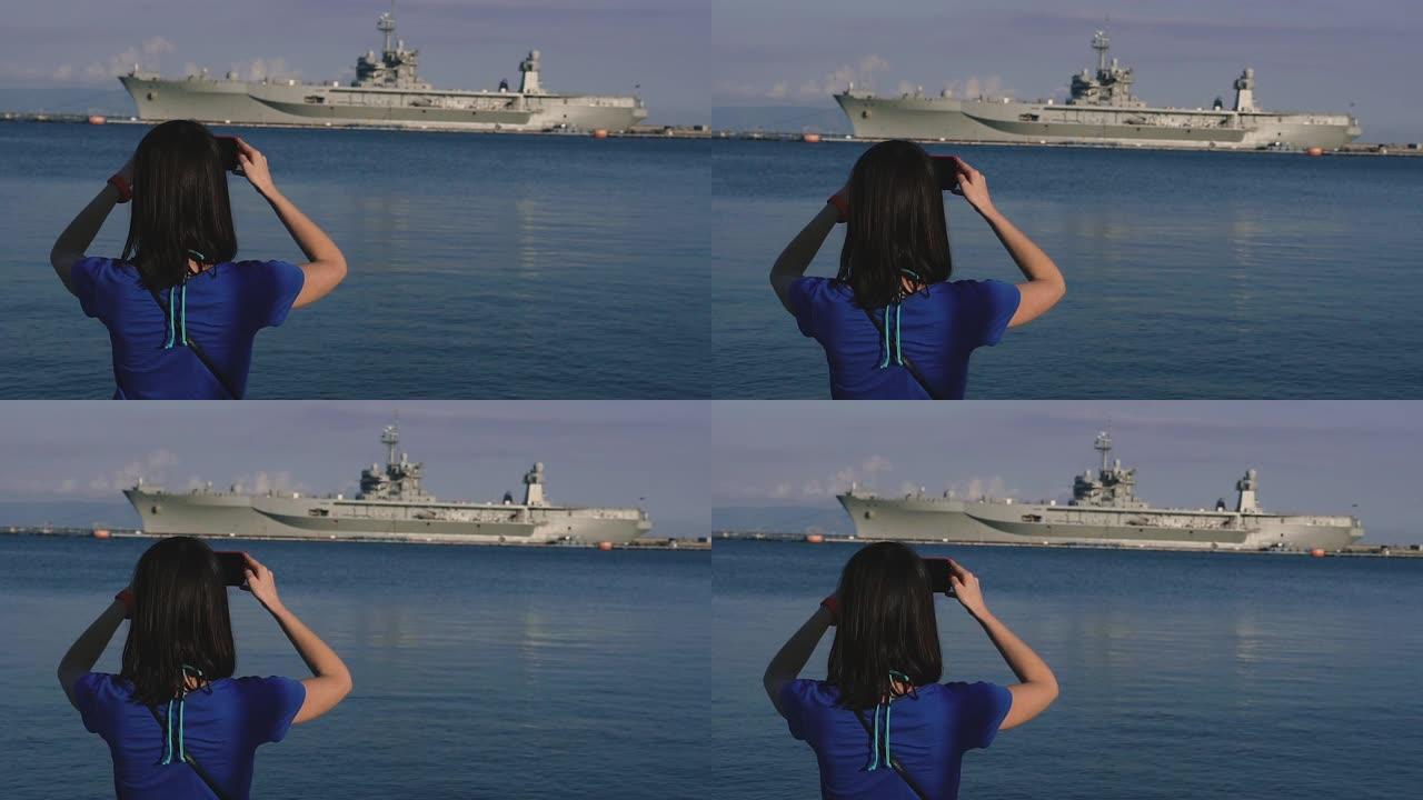 军舰。一个女孩用手机拿军舰。