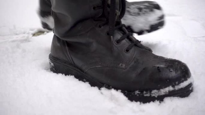 男人穿着沉重的靴子有力地踏在雪地上