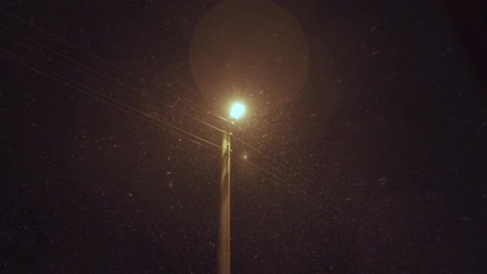 路灯照亮夜间降雪，初雪落下。