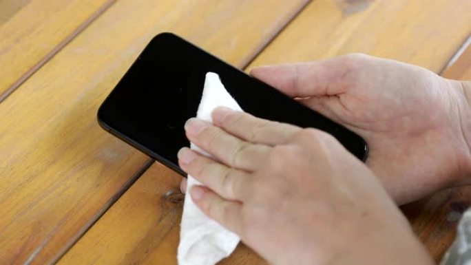 使用抗菌湿巾消毒手机的人手特写
