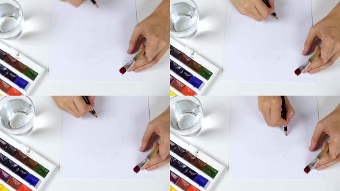 面目全非的女人在纸复活节卡片上画铅笔素描。桌子上是一个带有油漆和一杯水的调色板