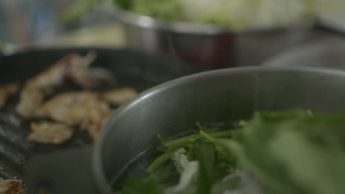 生猪肉和鱿鱼在锅里烧烤。在火锅中准备混合蔬菜汤。用餐时间。