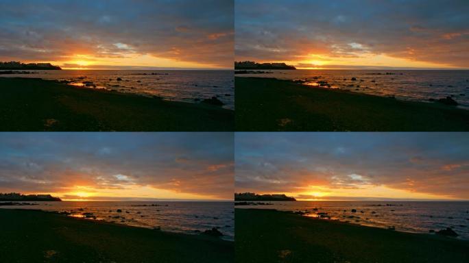 五颜六色的明亮戏剧性的日落，海洋上的黎明。太阳从地平线外升起，用射线照亮大海。多色的天空是橙色，黄色