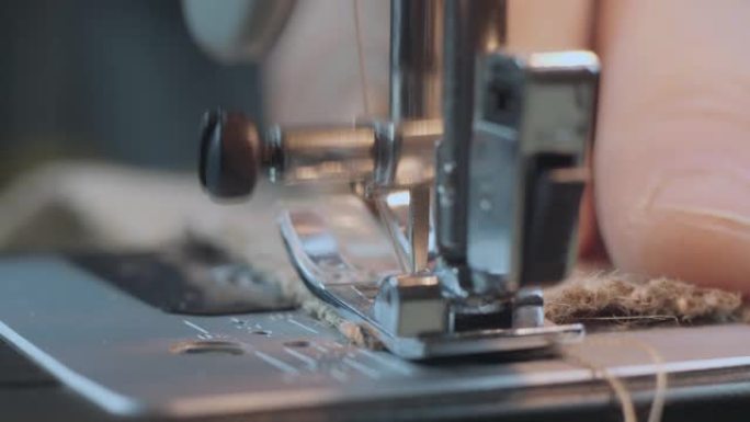 在缝纫机上近距离用粗麻布缝制。用缝纫机修理织物。手工服装工业概念。4k视频