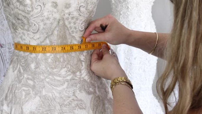 时装设计师在人体模型上测量婚纱