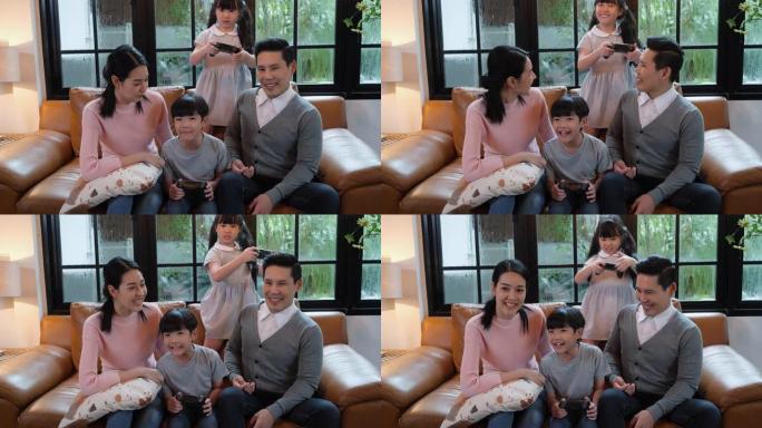 亚洲家庭周年快乐。活跃的父母和可爱的孩子儿子和女儿在现代房子的客厅玩电子游戏。玩得开心的男孩和女孩在