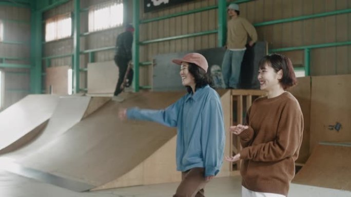 年轻的日本女滑冰者在滑板场互相问候