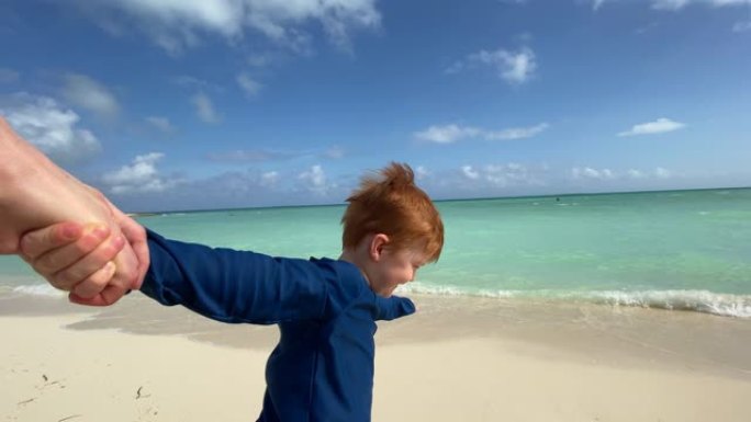 跟随我的概念 -- 在加勒比海的热带海滩上，红发男孩牵着母亲的手