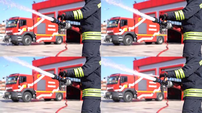 一名消防员正在使用消防水带灭火。特写和4k视图。红色和消防车背景。