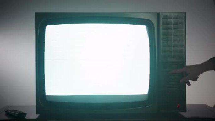 老式电视在黑暗的房间里闪烁白屏，噪音干扰概念。电视监视器上的男性换手频道，电视坏了，旧技术
