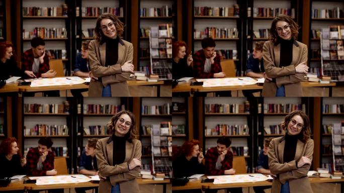 一位戴着眼镜和棕色夹克的迷人短发欧洲女学生站在高中图书馆微笑着看着相机微笑的肖像。教育、文学和人民观