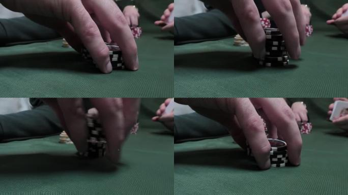 在绿布背景下的扑克牌桌上使用扑克筹码的男性手的特写镜头。休闲的概念