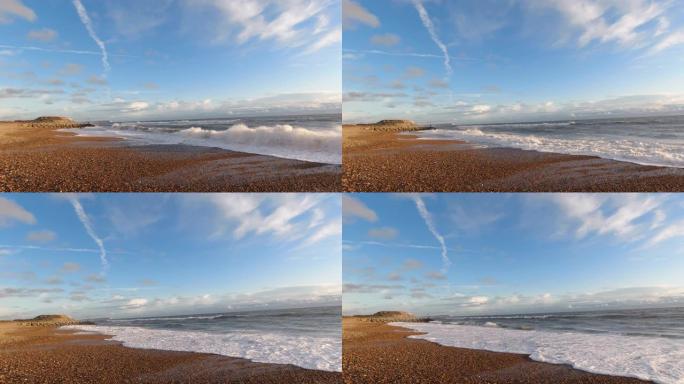 在雄伟的蓝天白云下，在石质海滩上拍打海浪的慢动作 (60 fps) 镜头
