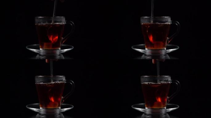 一块蔗糖放入热茶中，并用茶匙在黑色背景上的茶杯和茶碟中搅拌，慢动作