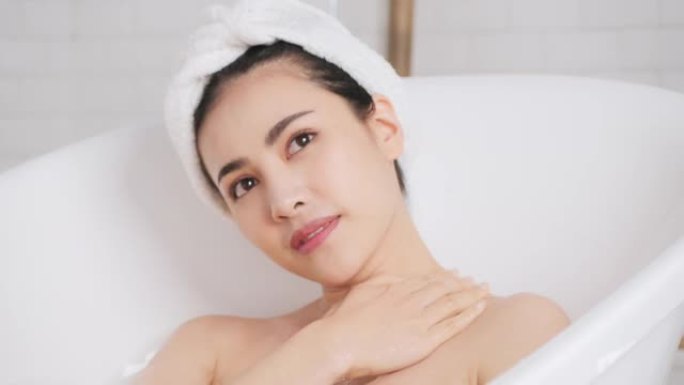 慢动作: 亚洲女性沐浴在她的身体上，选择性地集中在浴缸中的手和手臂上。
