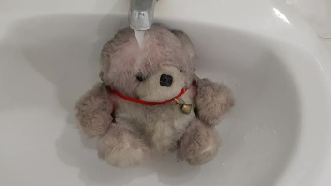 水在肮脏的泰迪熊上流动的镜头