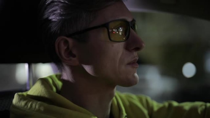 夜间戴黄色眼镜的男子司机的特写