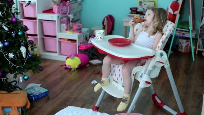 一个小女孩坐在儿童餐桌旁吃披萨。