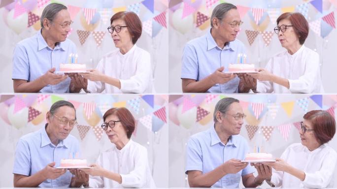亚洲老年夫妇在家里拿着蛋糕庆祝生日。老人在家里一起享受快乐时光。高级家庭在家的概念。