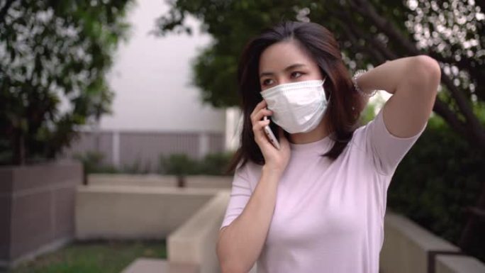 4k亚洲年轻女性在打电话和走路时戴口罩，严重的话题问题，预防疾病，社会问题，传播呼吸道疾病，公园外生