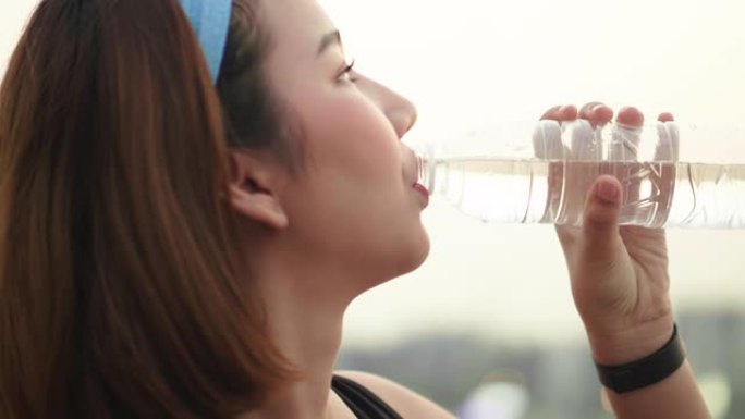 亚洲女子日落跑步后慢跑锻炼喝水