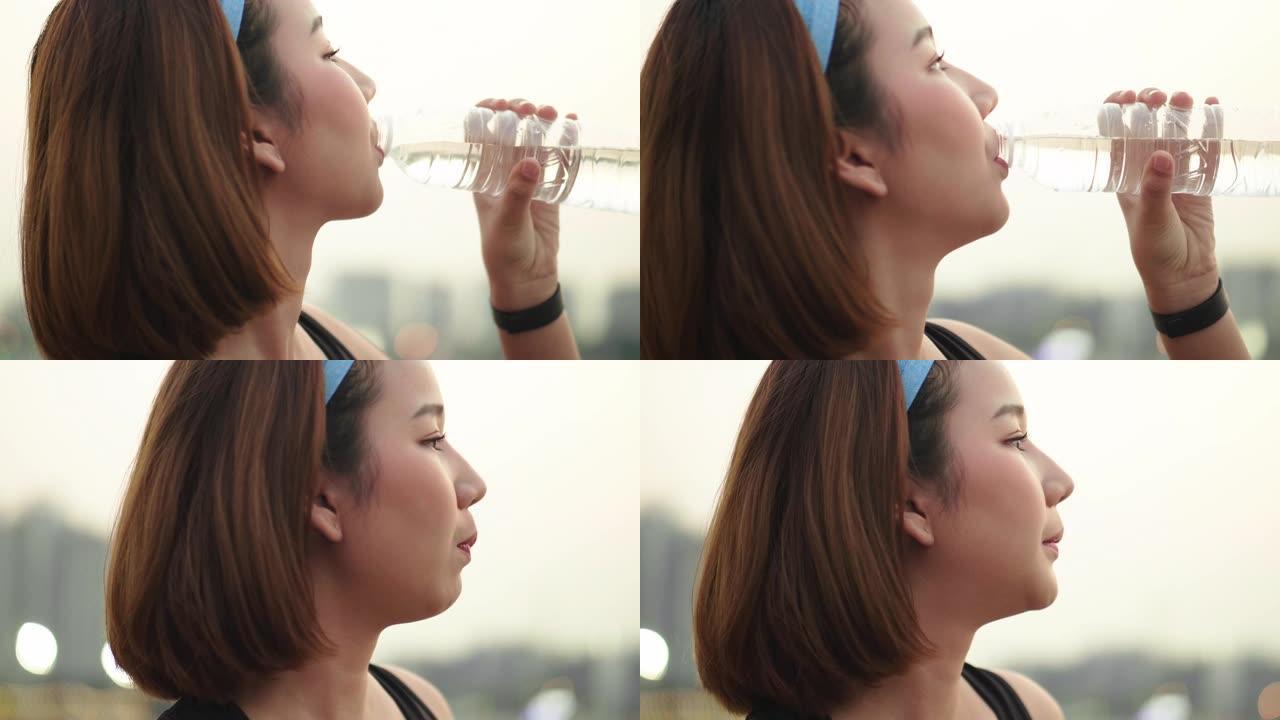 亚洲女子日落跑步后慢跑锻炼喝水