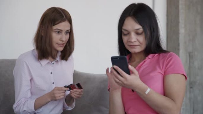 美国成年女性使用坐在家庭房间沙发上的电话在线付款