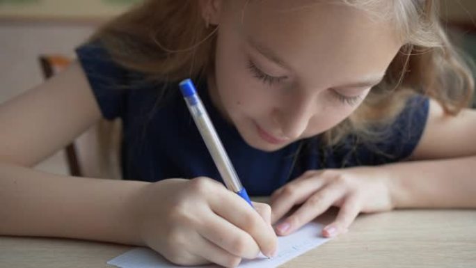 女学生在课堂上用钢笔在方格纸上写字。关闭学生女孩在桌子上的方格纸上写字。