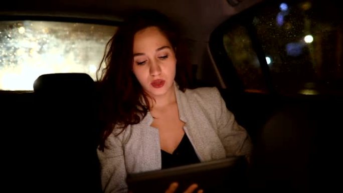 在出租车后座上使用数字平板电脑的女人