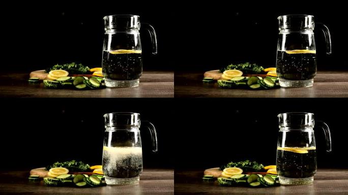 将柠檬黄瓜和薄荷叶切成薄片，放在装有苏打水的玻璃水瓶旁边的木制切菜板上。男性手在一杯苏打水中扔柠檬片