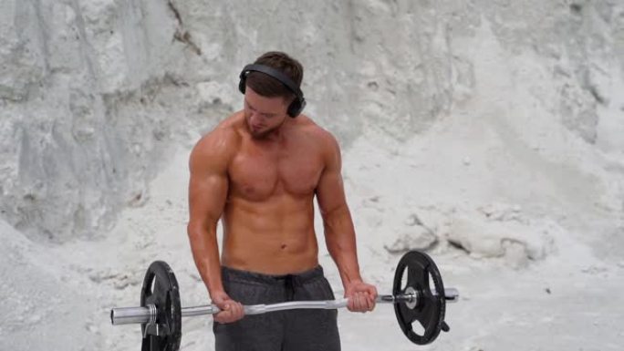 集中肌肉发达的人在山上用沉重的杠铃锻炼。
