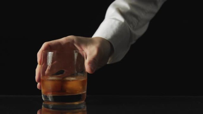 一个男人的手拿着一杯黑色的威士忌背景