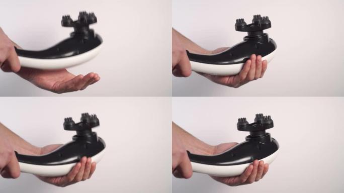 一个年轻人用带有凸起喷嘴的黑色白色电动振动按摩器敲他的手