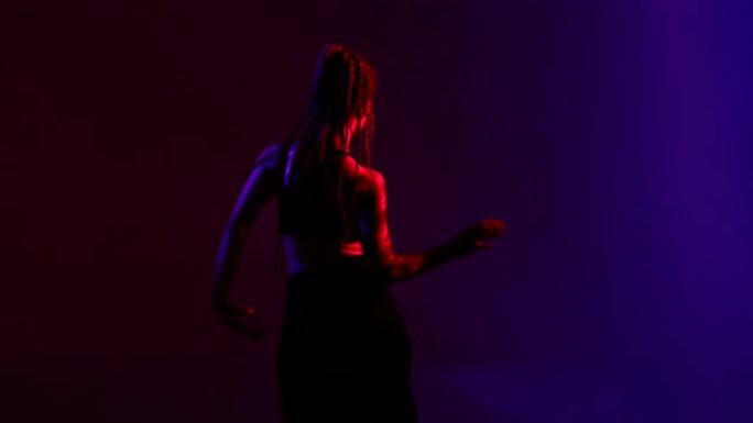 黑色打扮和辫子的女人东方在蓝色和红色的背景上跳舞。